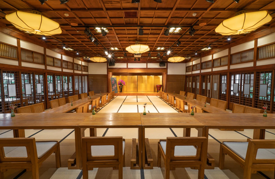 A traditional Japanese-style room with wooden furniture, tatami flooring, and ceiling lights, arranged for a formal event.