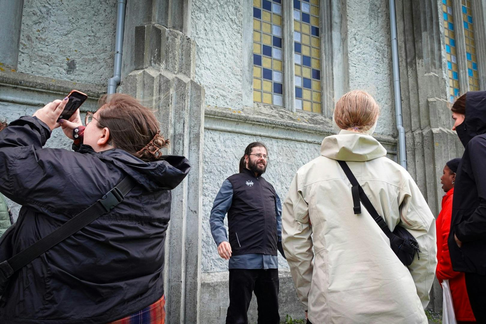 세 사람이 스테인드글라스 창문이 있는 석조 건물 근처에 서서 대화를 나누고 있습니다.