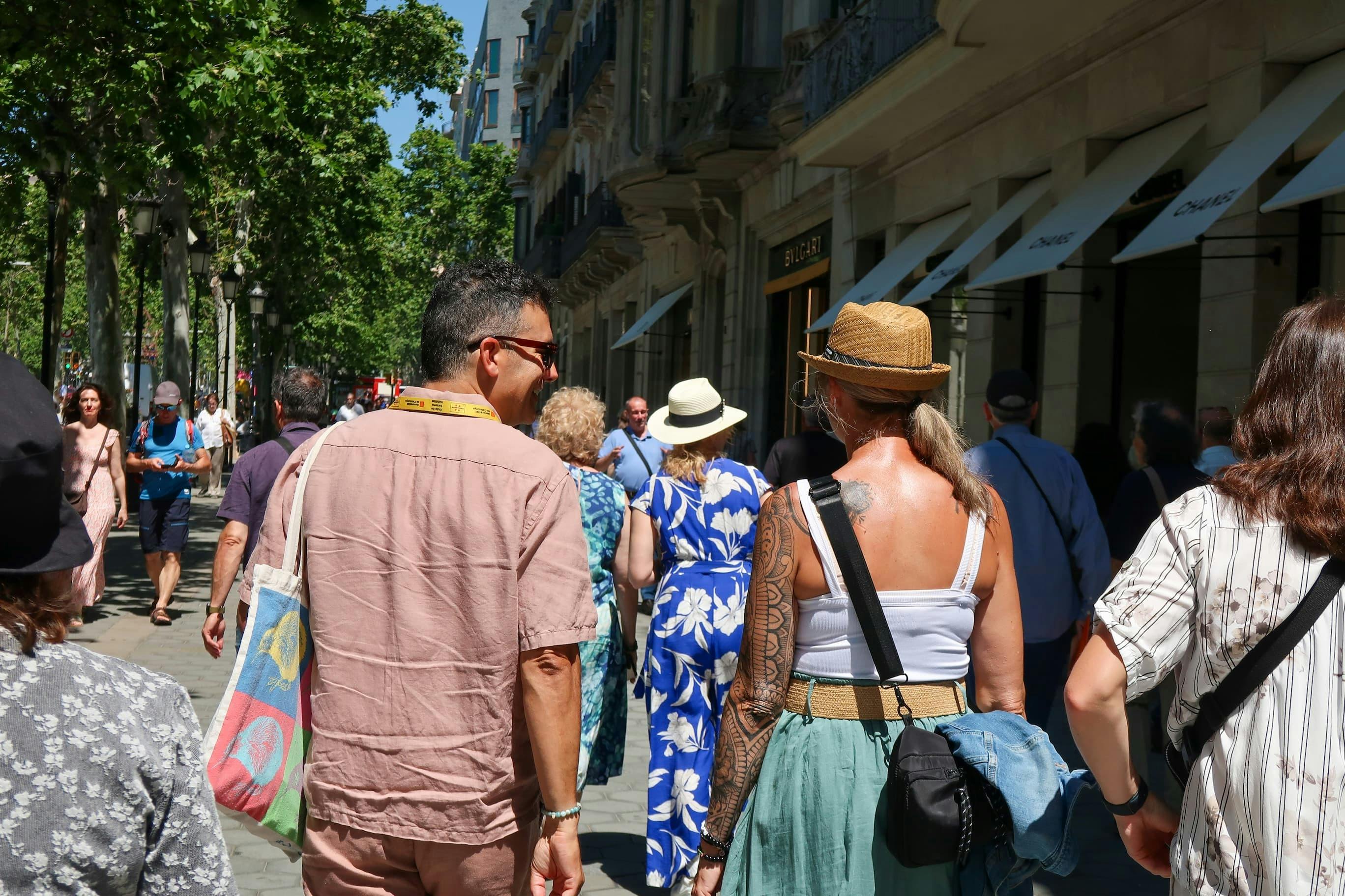 Les clients se promènent sur l'élégant Passeig de Gracia avec leur guide, entourés de boutiques de luxe et d'arbres feuillus.