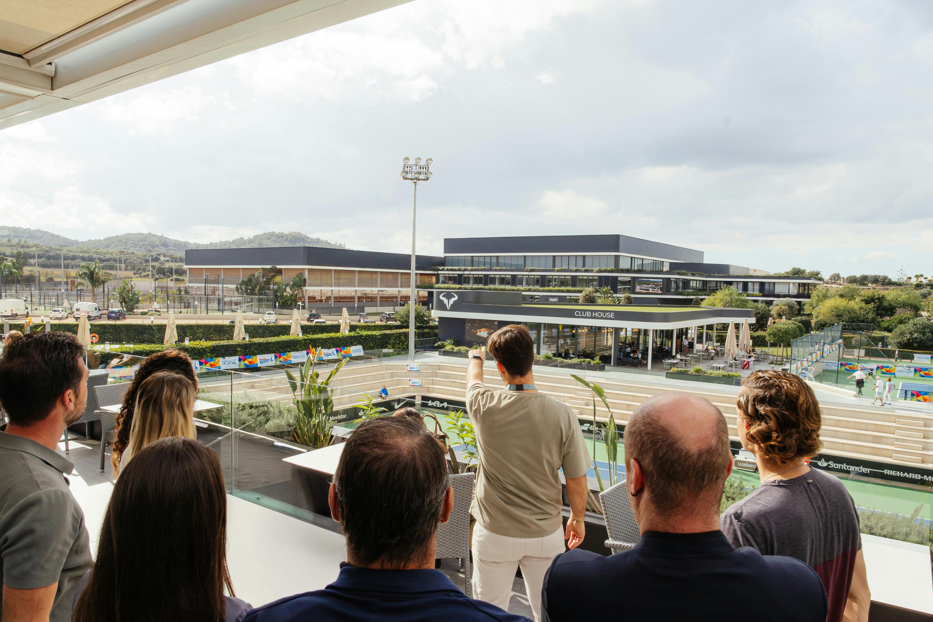 曇り空の下、バルコニーからモダンなクラブハウスやスポーツ施設を一望できる。