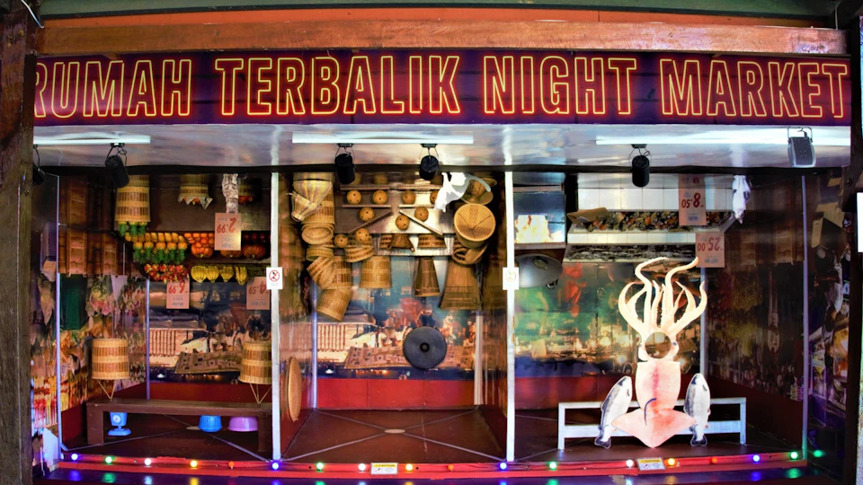 A colorful display from a night market, featuring baskets, food items, and decor under a sign reading "Terbalik Night Market."