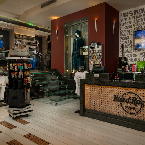 Insidan av en Hard Rock Cafe-butik med varor, inklusive T-shirts, ett skyltfodral med nålar, glastrappor och en disk med gitarr.