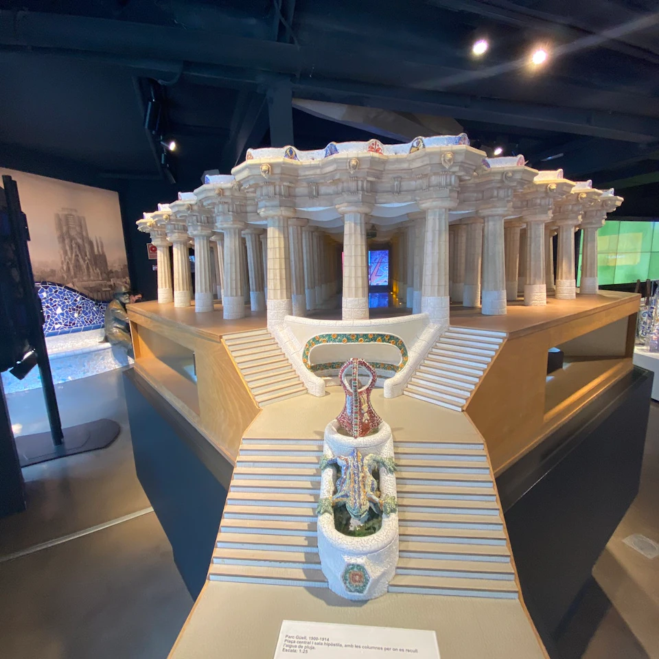 A detailed model of a classical building with columns, a staircase leading to an entrance, and an ornate statue in front.