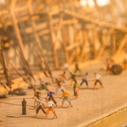 Ett diorama som visar miniatyrfigurer av arbetare som drar rep och arbetar på ett fartyg under konstruktion på ett varv.