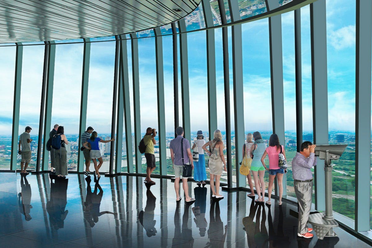 People standing and taking photos inside an observation deck with floor-to-ceiling windows offering a panoramic view of the city skyline.