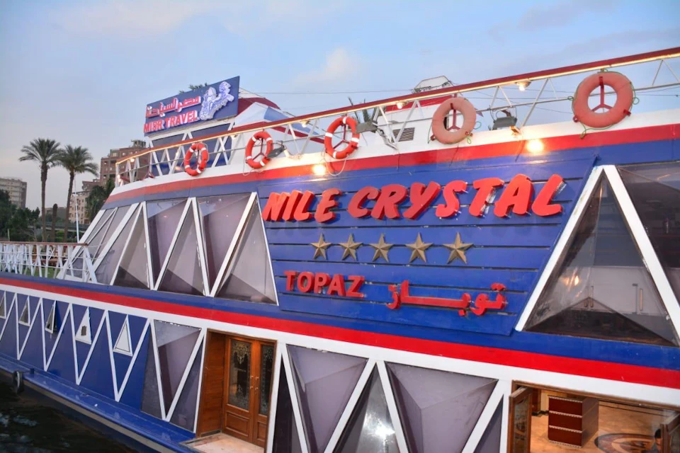 A colorful boat named 'Nile Crystal' with a geometric facade, seen docked under a clear evening sky.