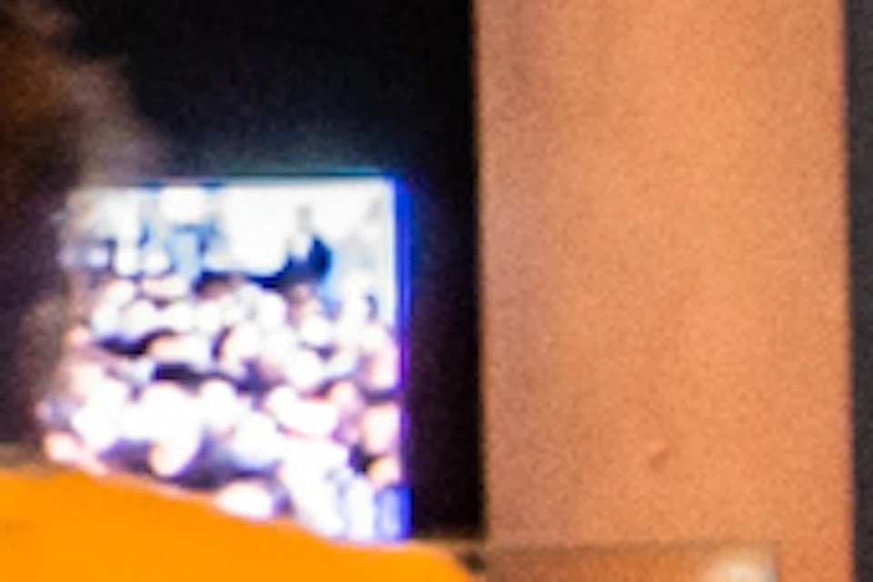 People interact with audio stations in a dark room with multiple large screens displaying various images.