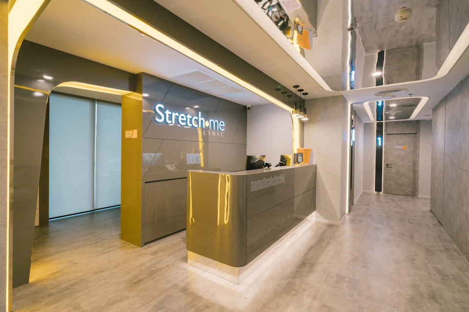 A modern clinic reception area with a sleek front desk, illuminated signs, and contemporary design elements.