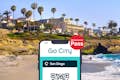 San Diego All-Inclusive Pass by Go City displayed on a smartphone with a San Diego beach in the background