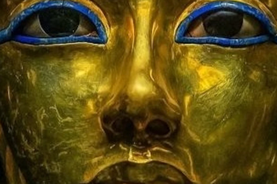 Golden mask of Tutankhamun with blue and gold striped headpiece and intricate facial details, on a black background.