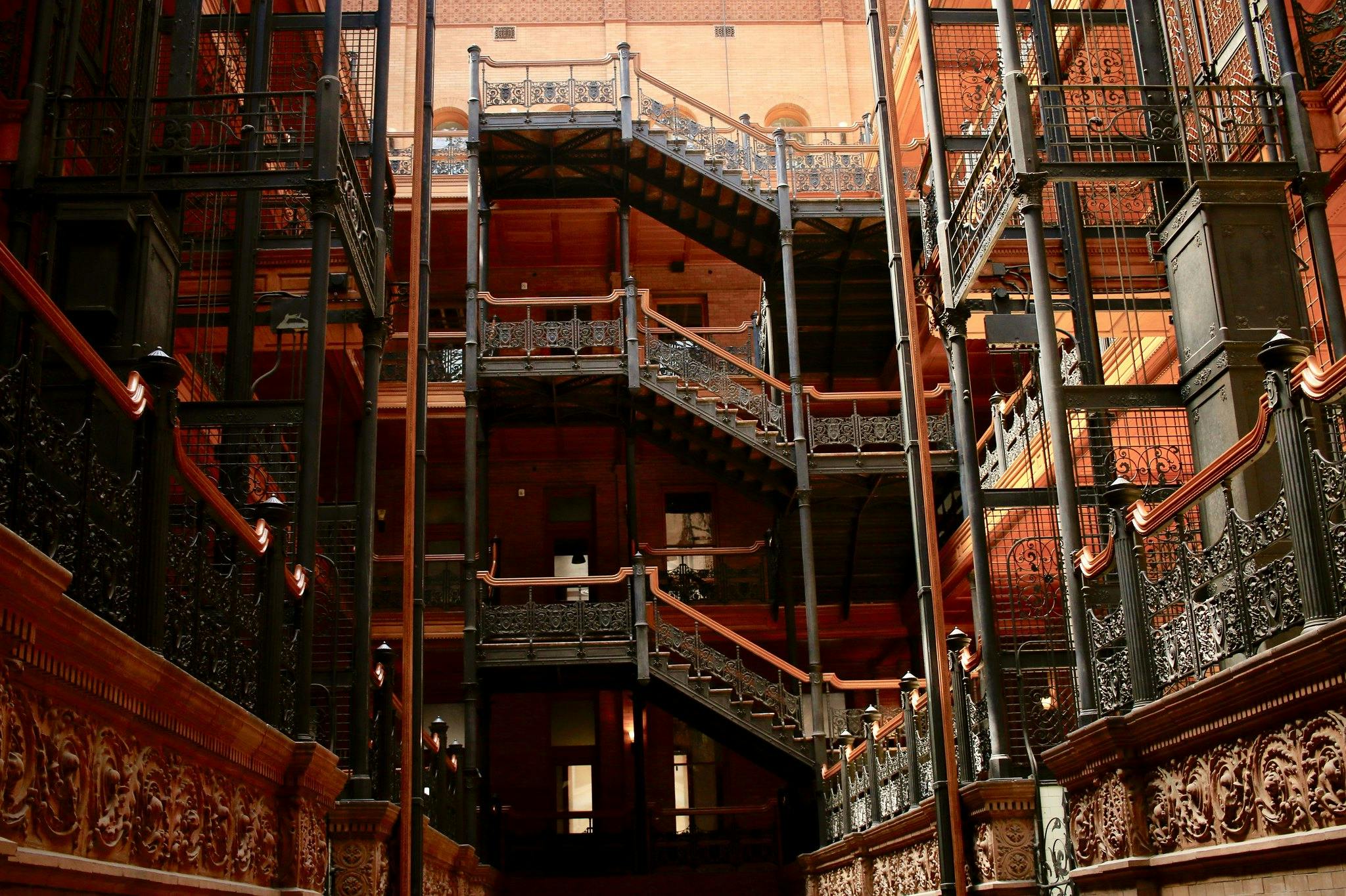 Ornate iron and wood staircases in a multi-story, industrial-style interior with decorative railings and detailed brickwork.