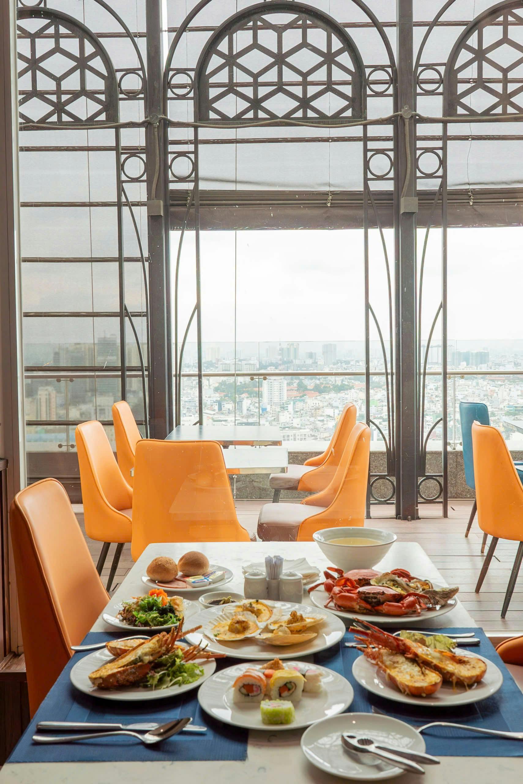 A restaurant dining area with orange chairs, a table set with food, and a large window showing a cityscape view.