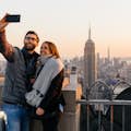 Homem e mulher tiram selfie com o Empire State Building ao fundo, na plataforma de observação do Top of the Rock