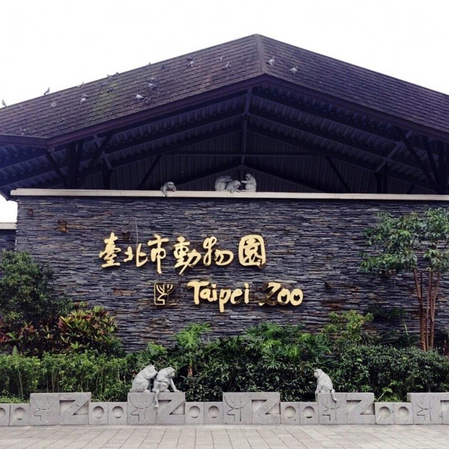 L'entrée du zoo de Taipei avec un panneau en caractères chinois traditionnels et en anglais, entouré de verdure et de sculptures.