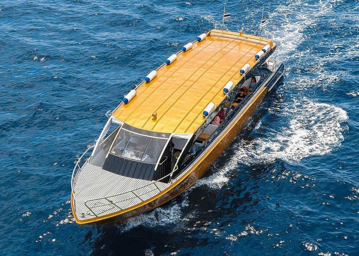 Μια βάρκα με κίτρινη στέγη πλέει σε καταγάλανα νερά. Αρκετοί άνθρωποι είναι ορατοί μέσα στο σκάφος. Οι σημαίες είναι τοποθετημένες στο πίσω μέρος.