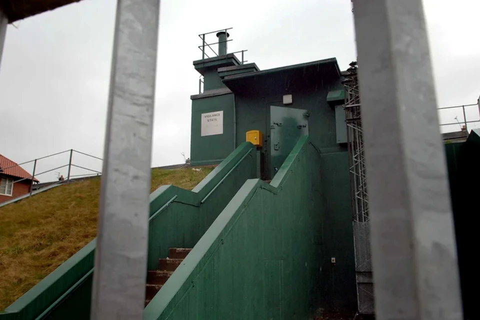 A green building labeled "VORGANCE SIGNAL" with stairs leading up to a door, observed through a metal fence.