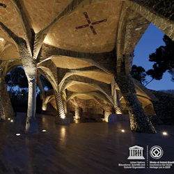 Svagt upplyst arkitektonisk struktur med böjda tegelväggar och pelare, invecklade takmönster och små lampor på golvet.