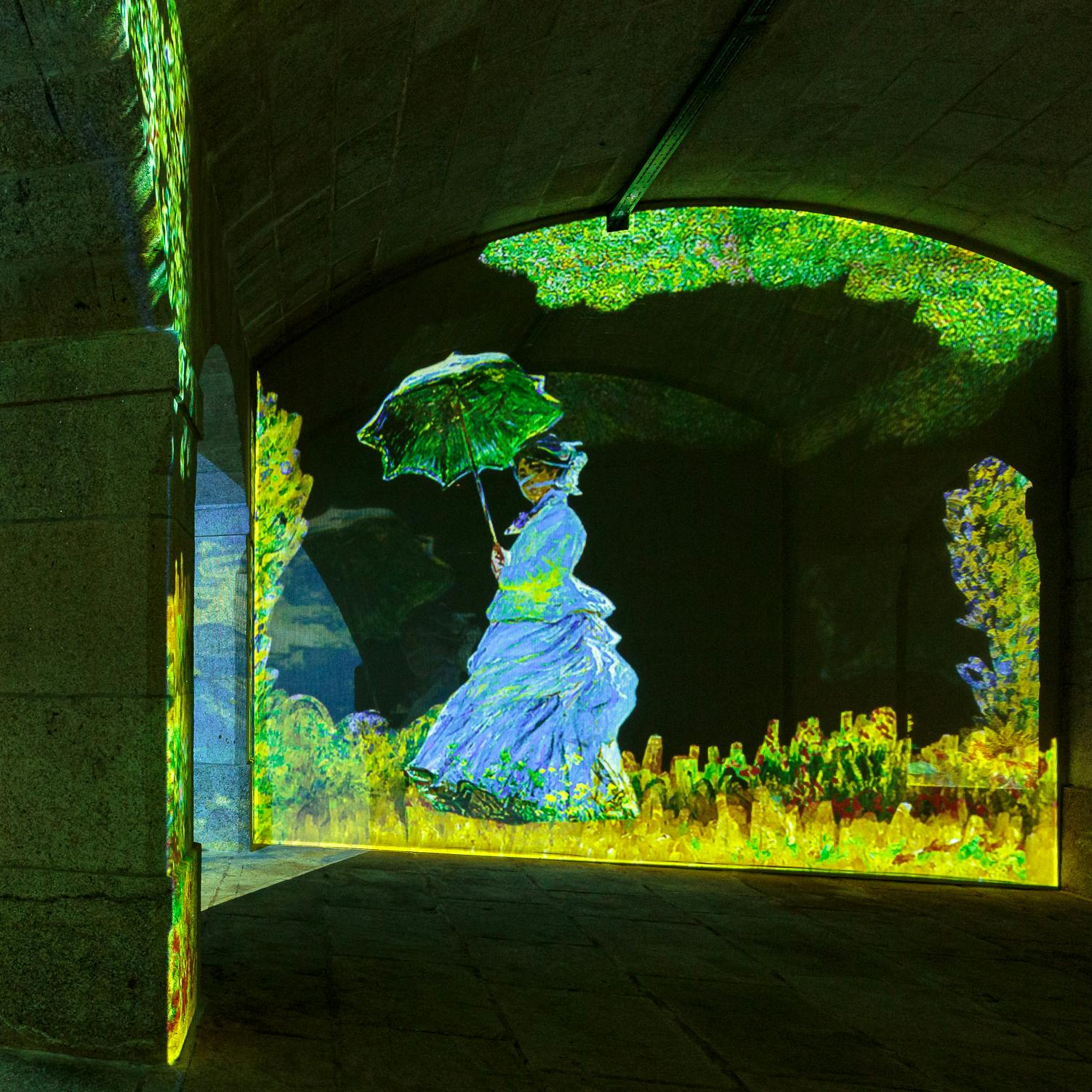 暗い部屋の壁に表示される鮮やかでカラフルな背景にパラソルを持った女性のデジタル投影。