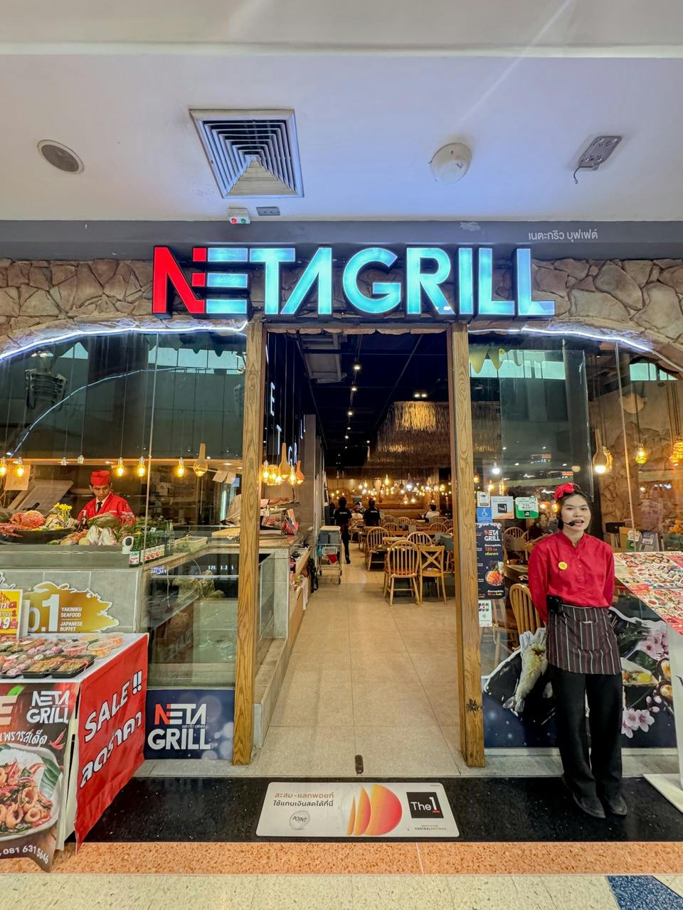 Front view of a restaurant named Neta Grill with a hostess standing outside and a visible interior dining area.