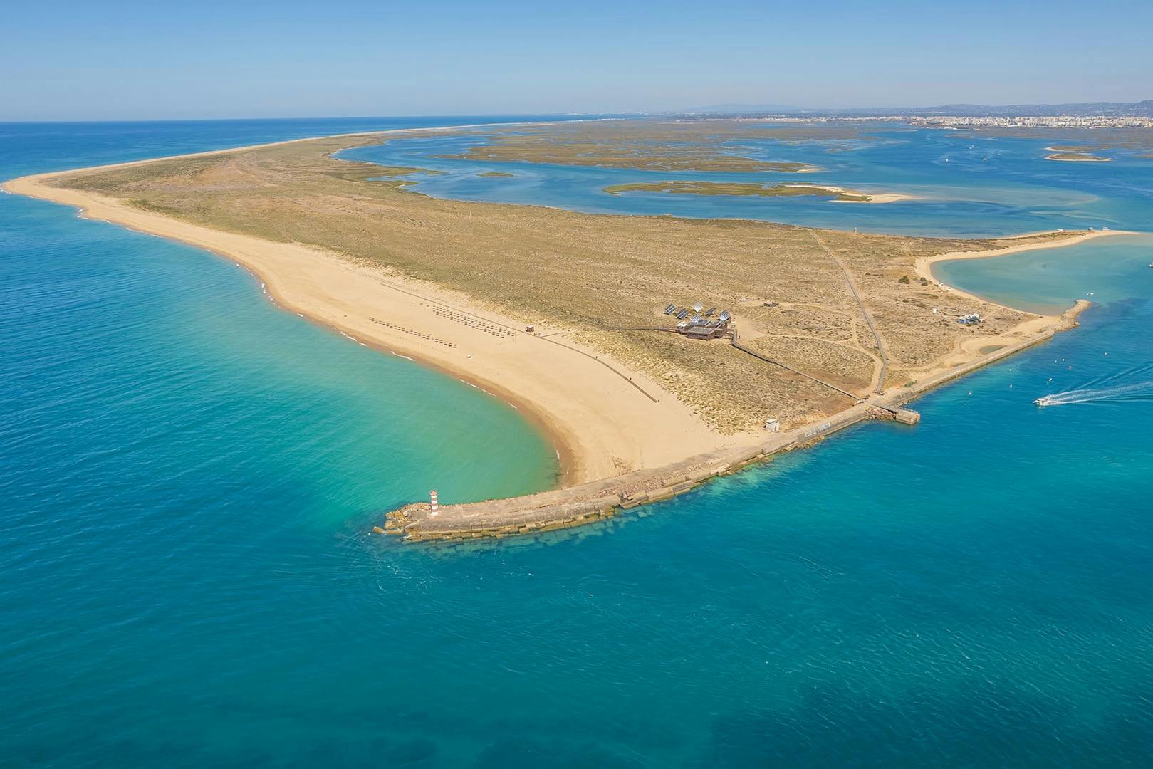 Вид с воздуха на остров Дезерта с чистыми бирюзовыми водами, небольшим пирсом и живописным прибрежным ландшафтом под ярко-синим