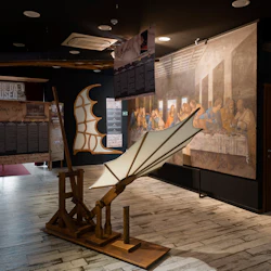 Utställning som visar Leonardo da Vincis uppfinningar med en modell av en flygmaskin och en reproduktion av "The Last Supper" på väggen.