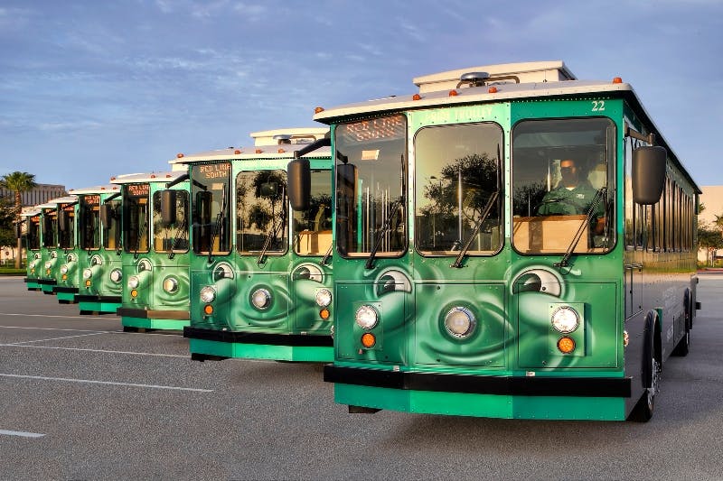 Tři zelené vozíky zaparkované vedle sebe na silnici pod jasnou modrou oblohou.