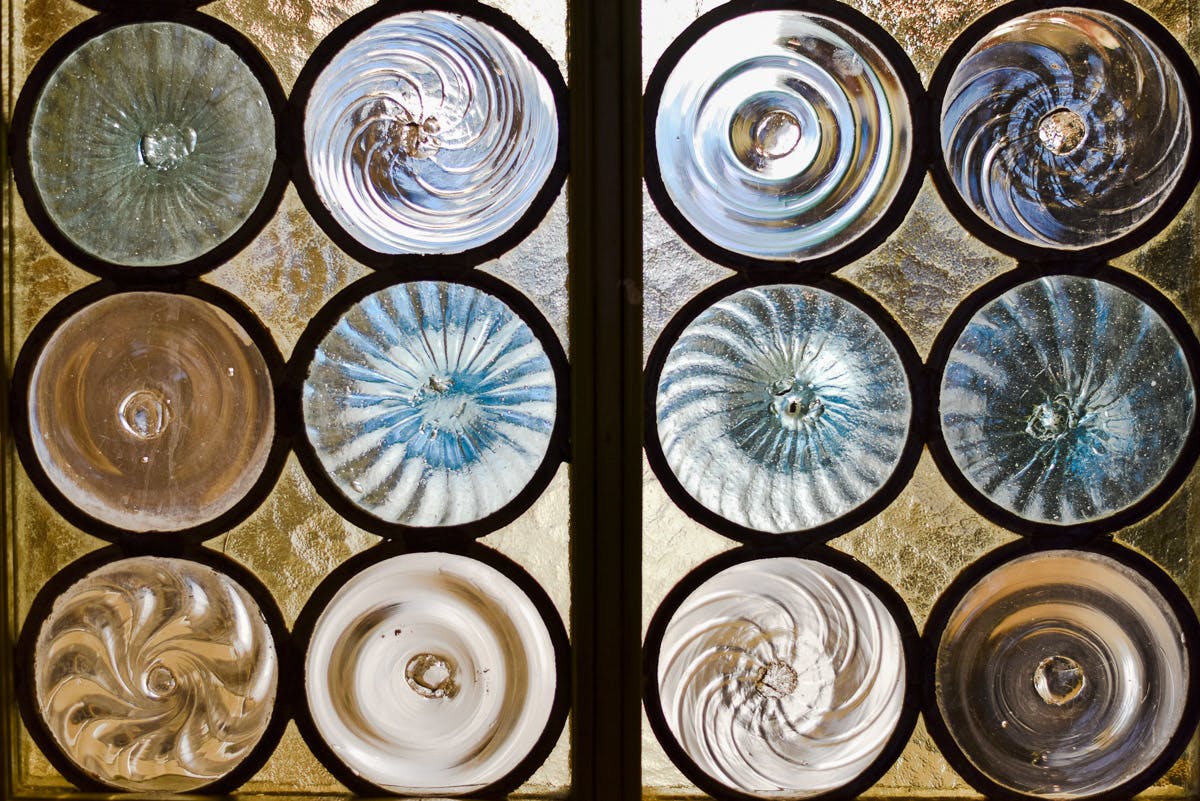 Gros plan sur un vitrail dont les vitres sont circulaires et tourbillonnantes, dans des tons bleus et clairs.