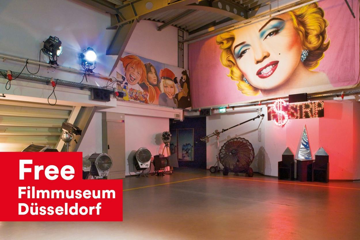 Ein Innenraum mit farbenfrohen Wandmalereien und einer eklektischen Dekoration, darunter ein großes Kunstwerk zum Thema Marilyn Monroe an der Wand.