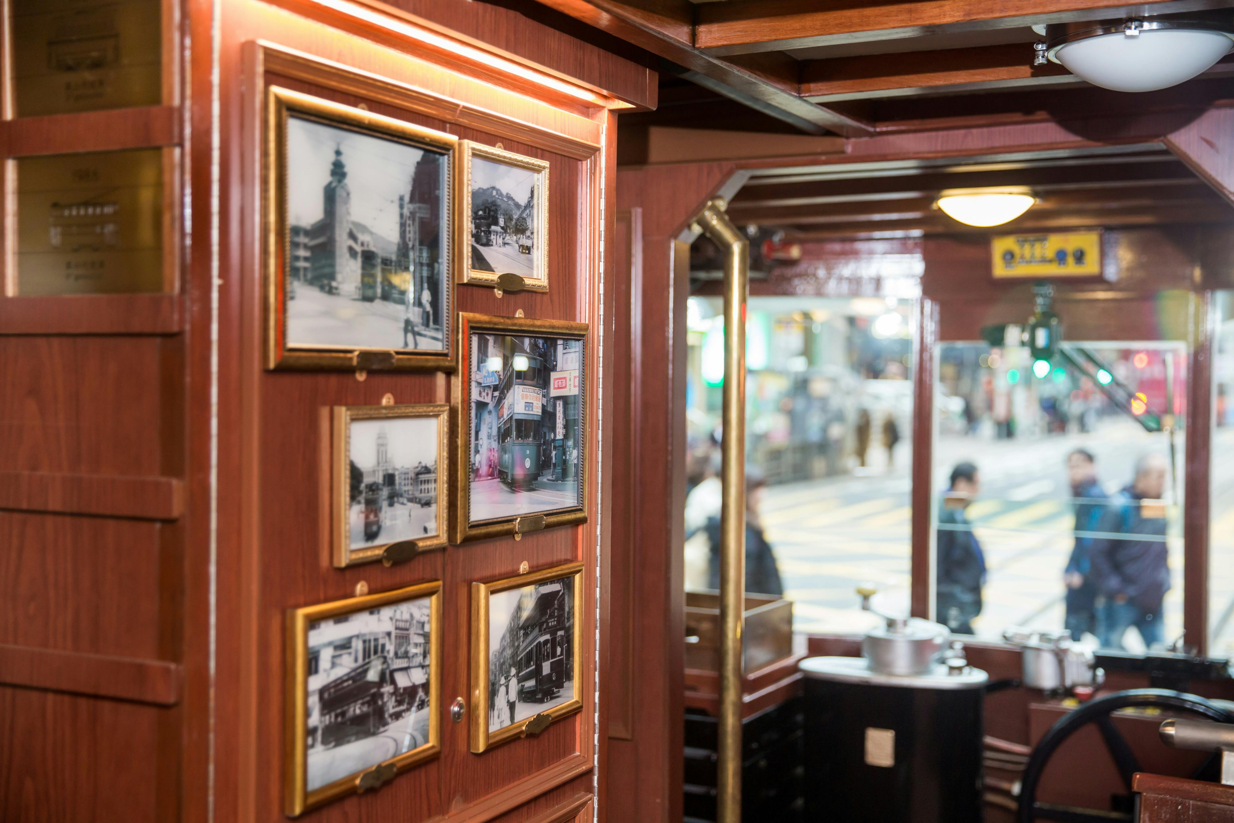 A wooden interior wall with framed black-and-white photos, a mirror reflecting a street view, and part of a restaurant setup.