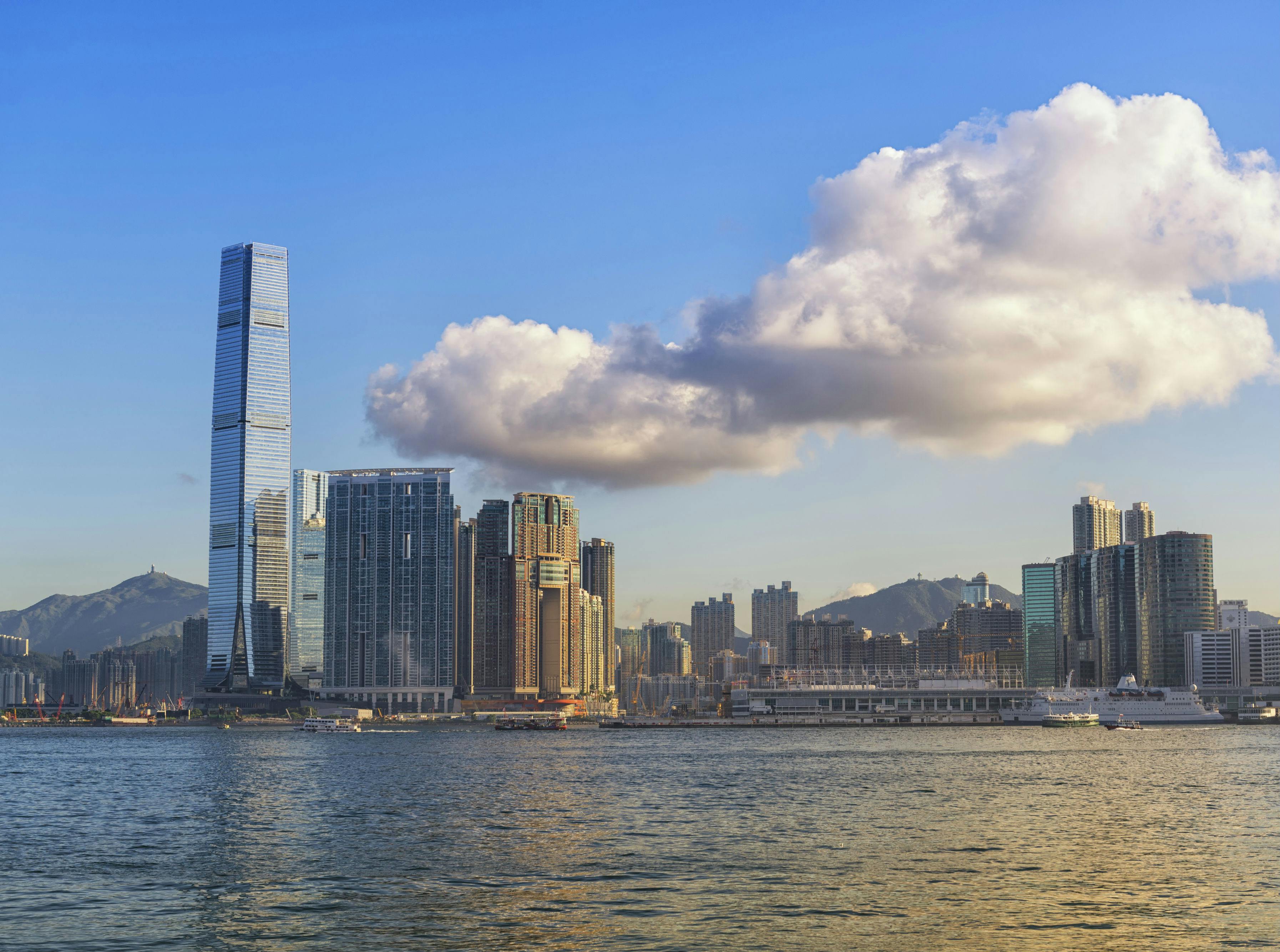 高層ビルが建ち、空に大きな雲が浮かぶ街のスカイライン。水域を横切って見渡すことができます。