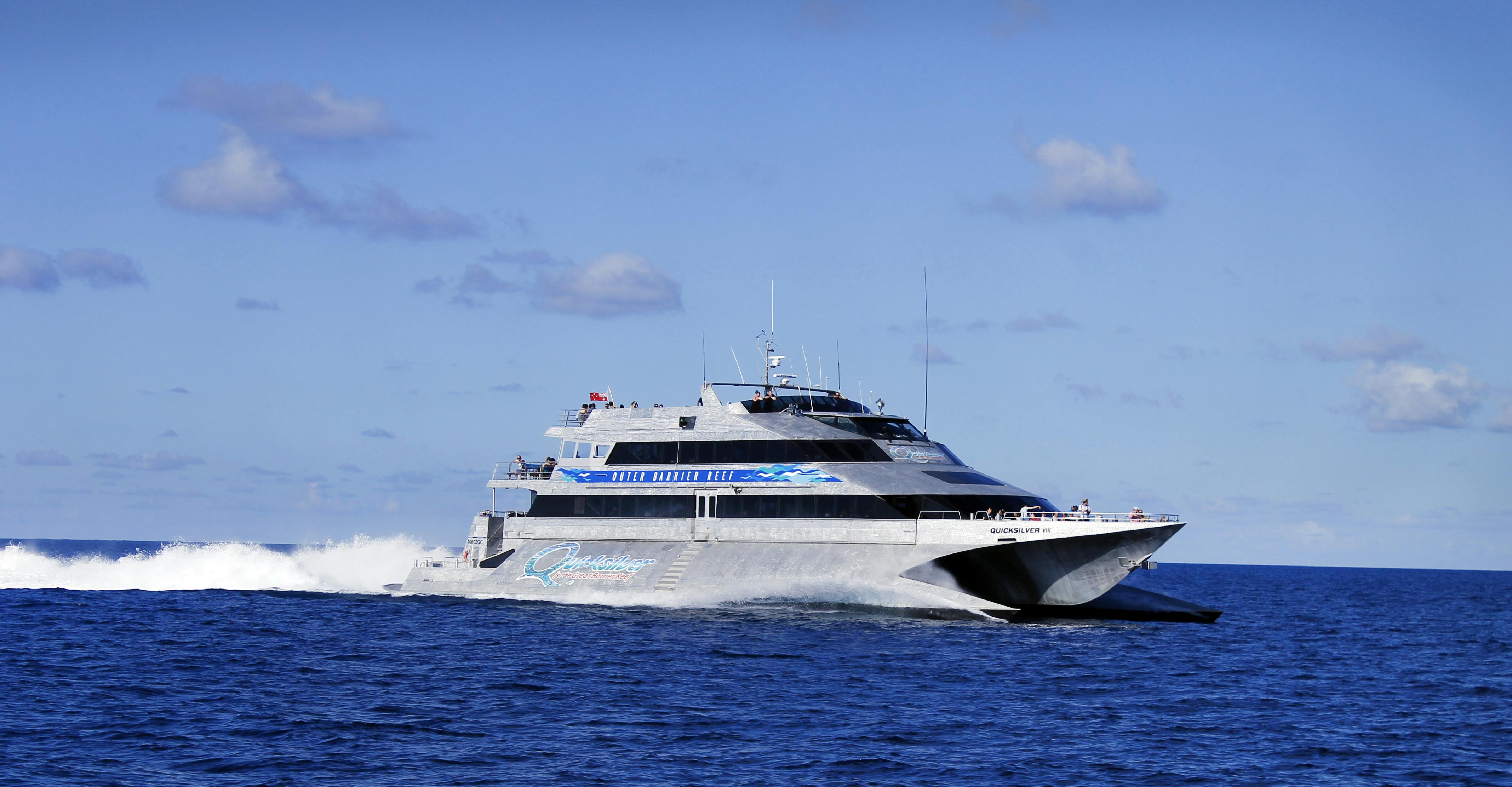 Ένα μεγάλο, σύγχρονο καταμαράν που διασχίζει τον ωκεανό σε μια καθαρή μέρα, με έναν γαλάζιο ουρανό και λίγα σύννεφα στο παρασκήνιο.