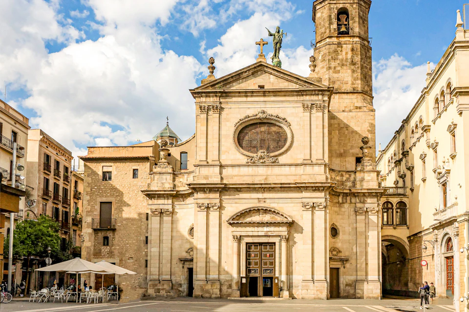 A historic stone church with ornate architecture and a tall bell tower under a partly cloudy sky.