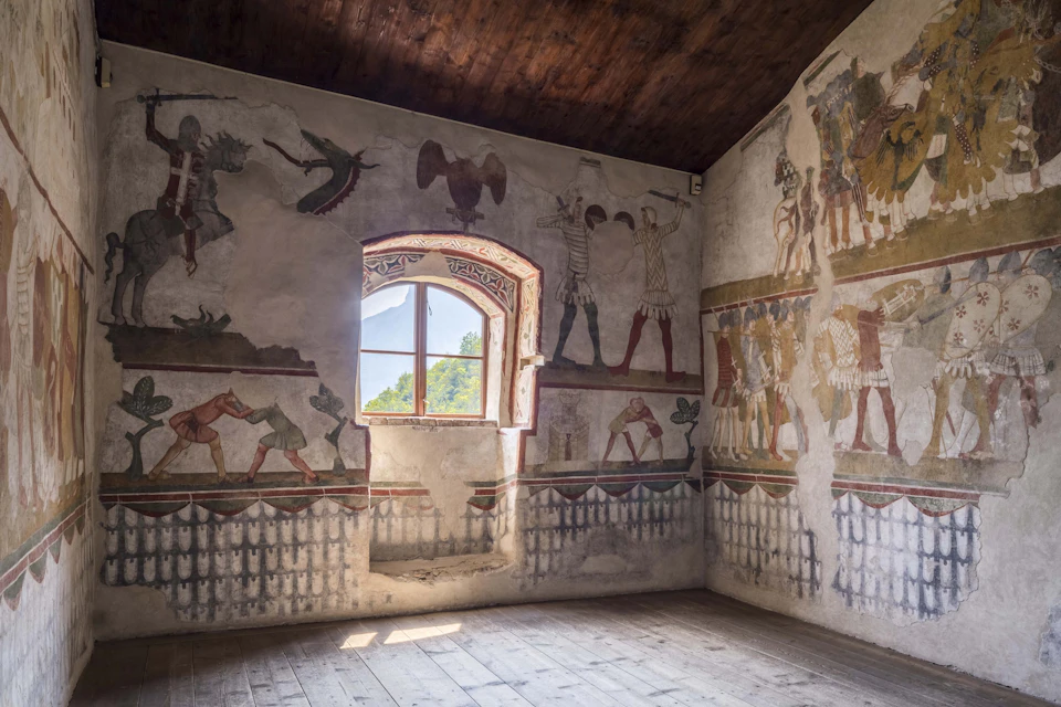 Room with rustic wooden floor and ceiling featuring wall murals depicting historical figures and scenes around a window.