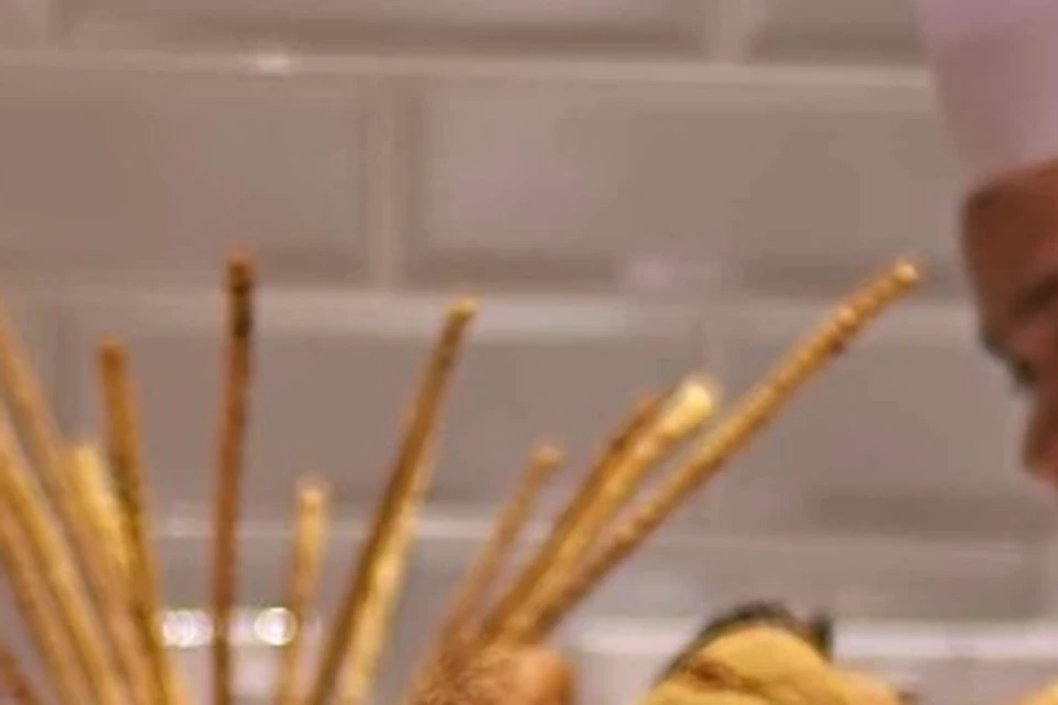 Chefs wearing white uniforms and hats prepare food behind a buffet counter with various dishes and drinks displayed.