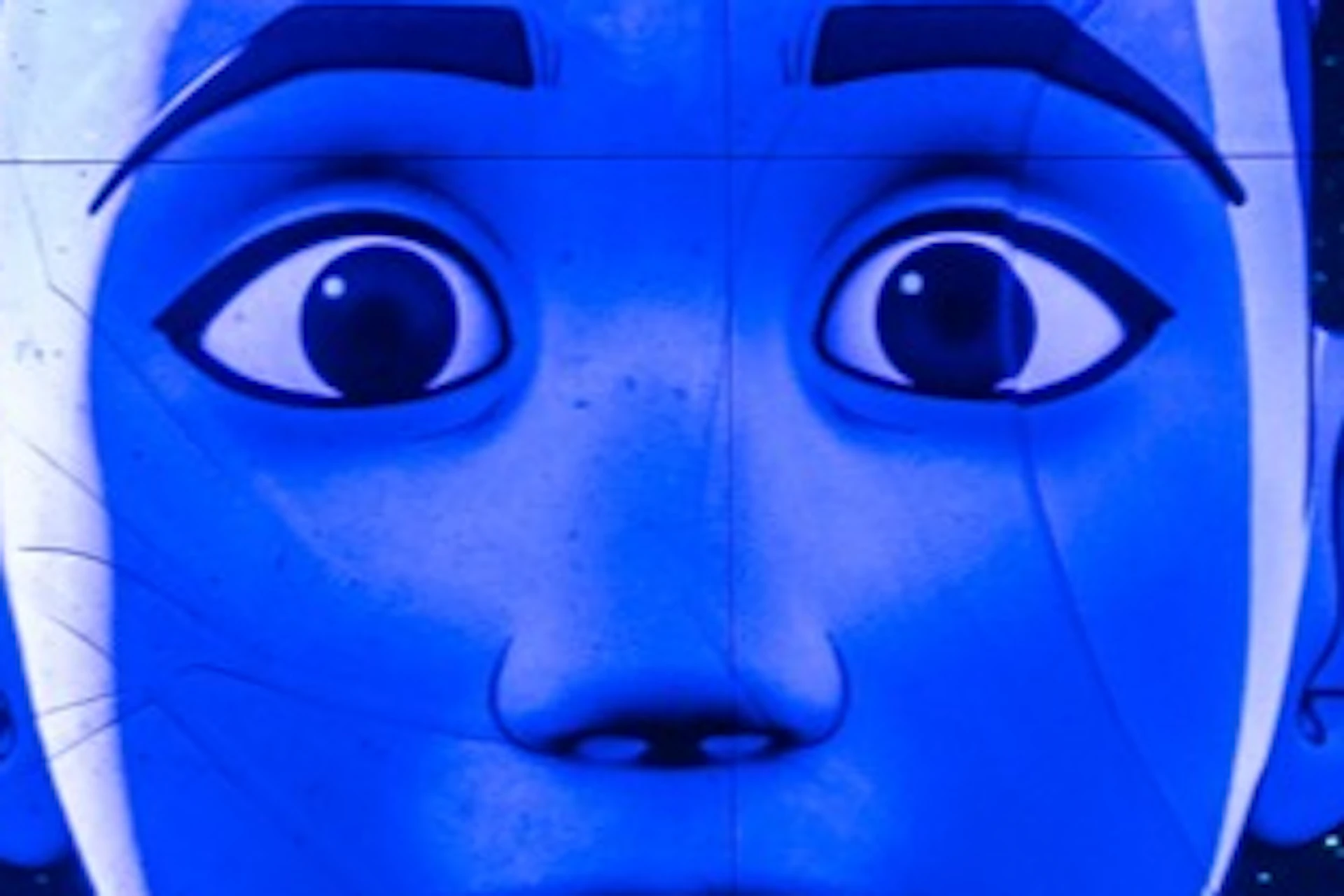 A digital installation of a stylized face with a blue hue, surrounded by starry visuals and illuminated walls in a dark room.