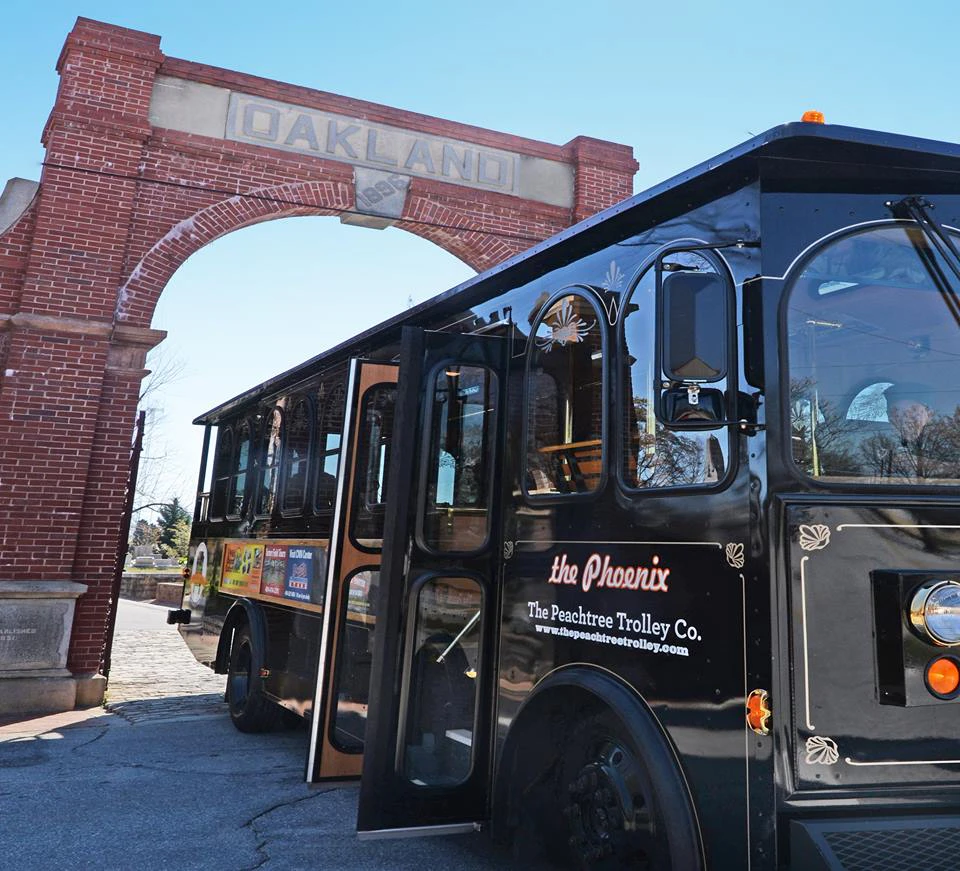 A black trolley labeled "the Phoenix" in front of a red brick archway with the word "Oakland."