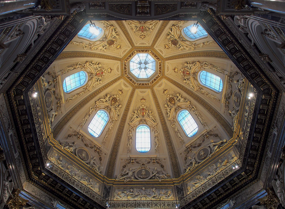 Ornate, domed ceiling with intricate sculptures and stained glass windows in a classical architectural style.