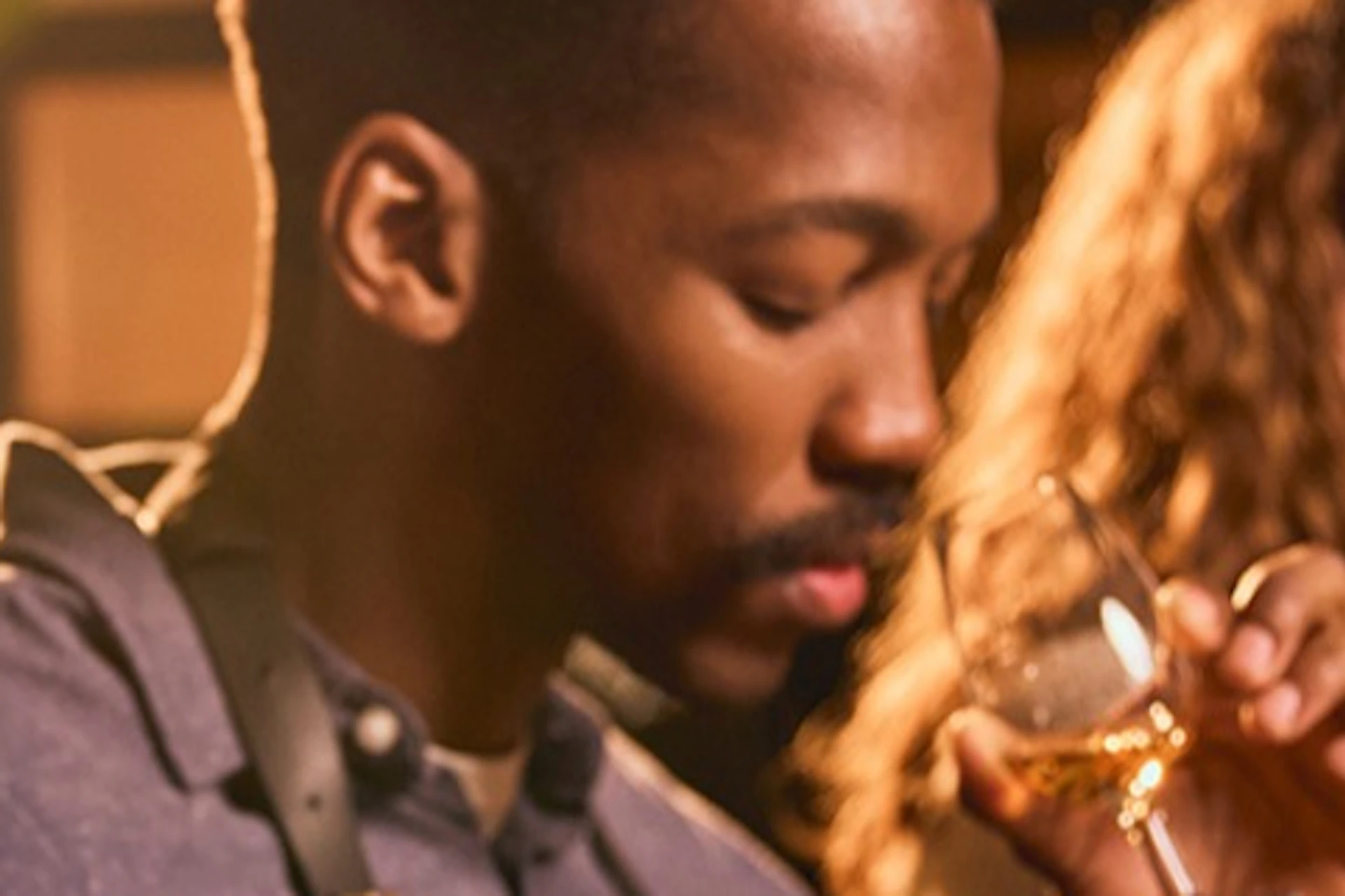 A group of people sampling drinks at a tasting event, each with glasses and pipettes, under warm lighting.