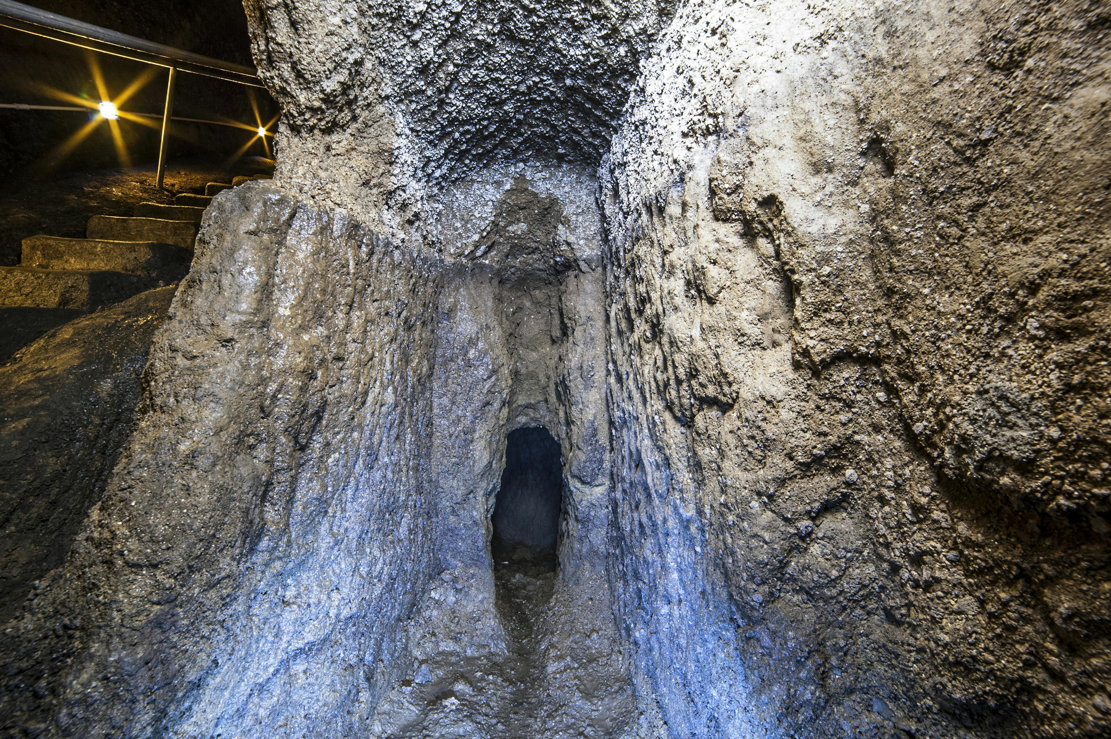 Smal stentunnel med ru, strukturerede vægge. Dæmpet belysning oplyser det hulelignende interiør.