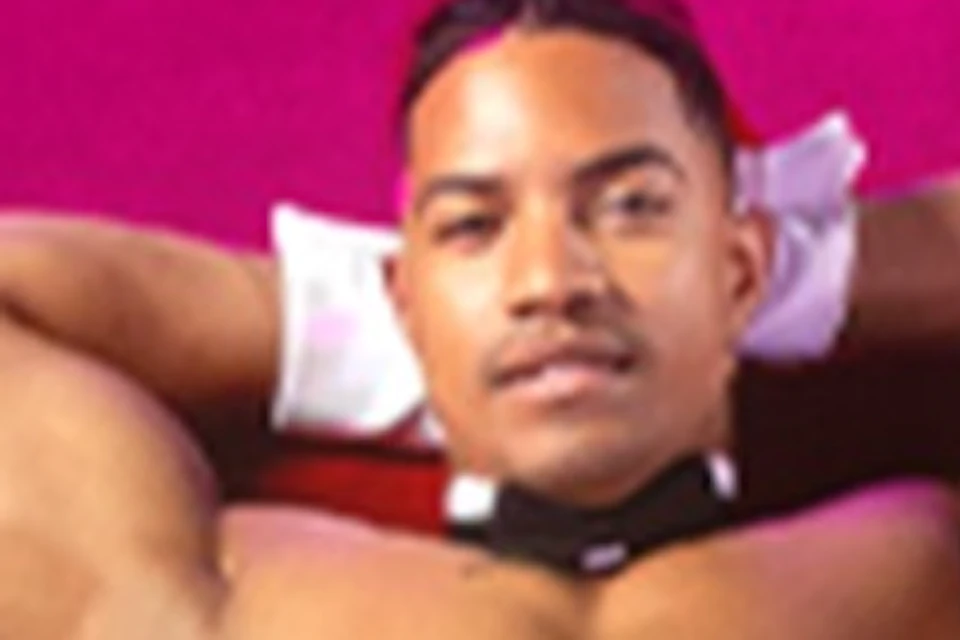 Five shirtless men in partially open blazers and jeans pose on a bright pink background.