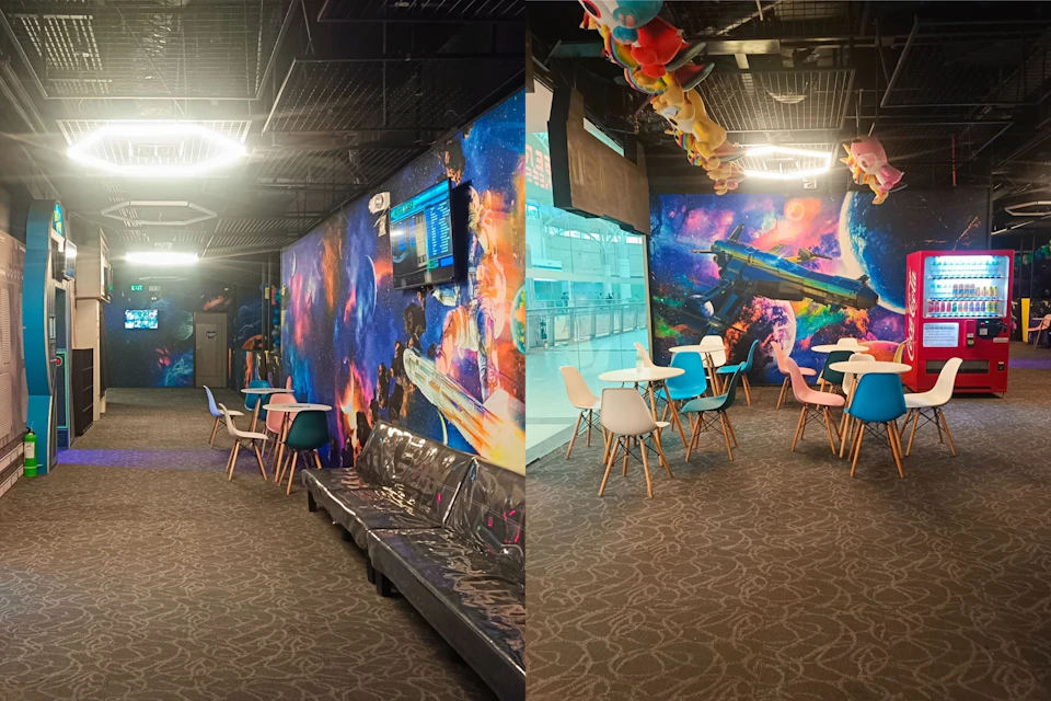 A colorful indoor seating area with space-themed wall art, chairs, tables, and a bench under bright ceiling lights.