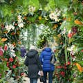 Two people walking under an archway made of greenery
