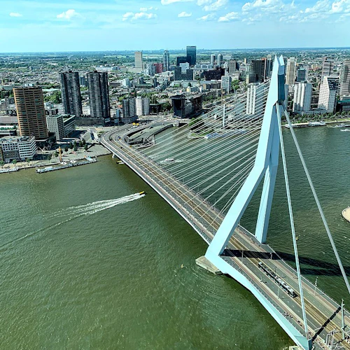 Flygfoto över en snedkabelbro över en flod, som förbinder ett stadsområde med många höghus.