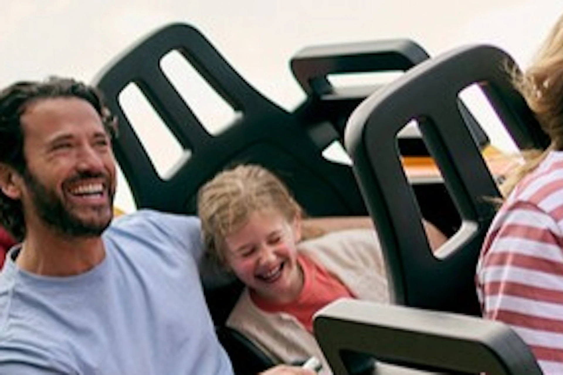A family enjoys a ride on a colorful roller coaster under a clear blue sky.