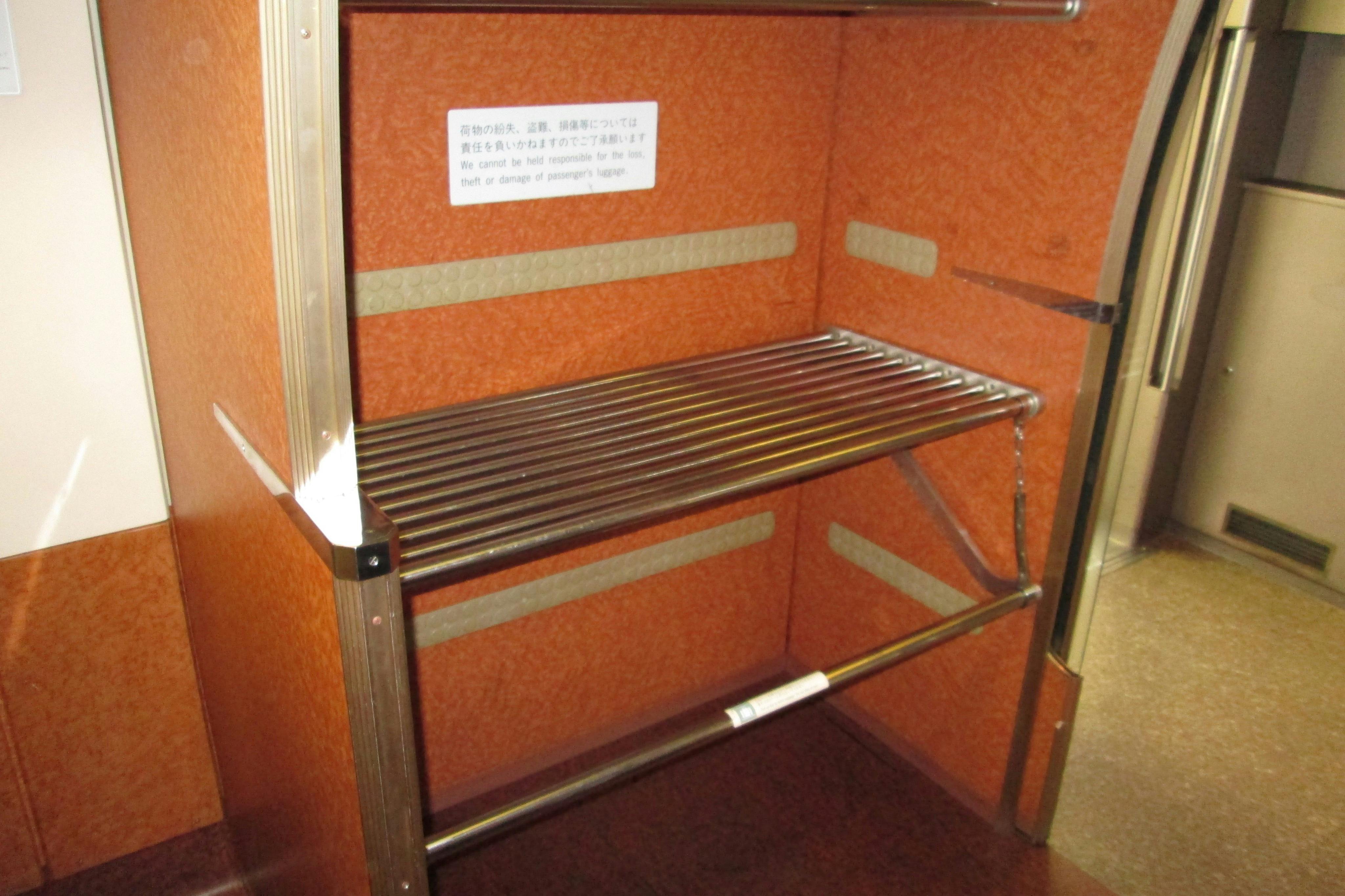 Nosič zavazadel s kovovými mřížemi a oranžovými stěnami s cedulí s informacemi o odpovědnosti za krádež.