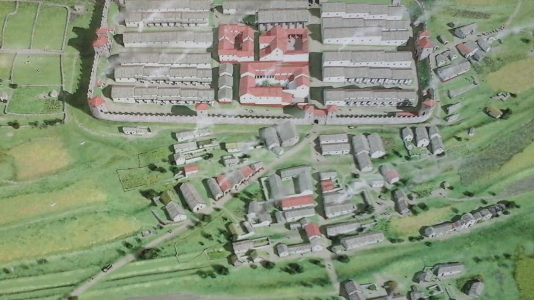 An aerial view of a detailed scale model depicting a small town with numerous buildings, roads, and green spaces.