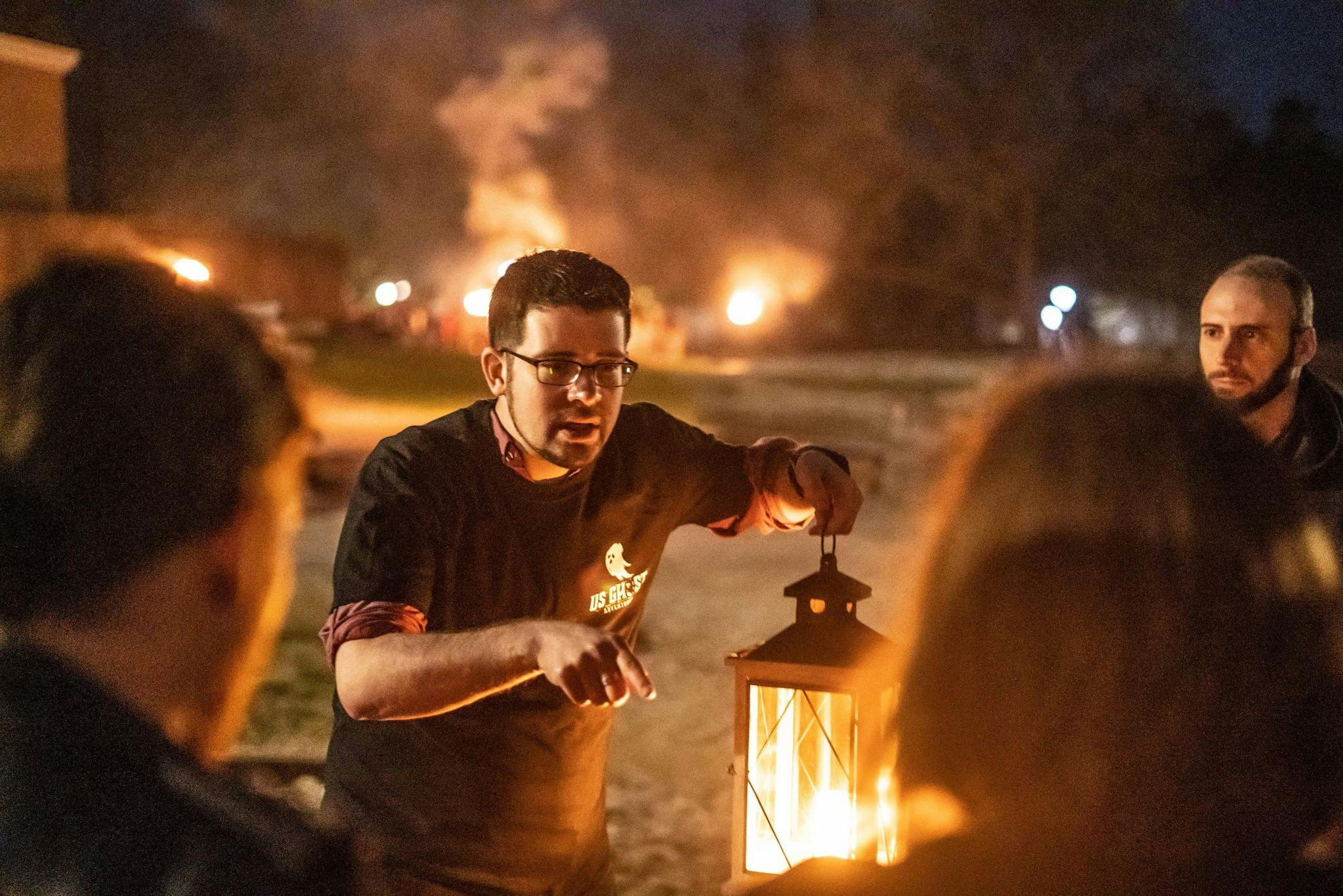 Tour guide telling ghost stories to his group while holding a lantern