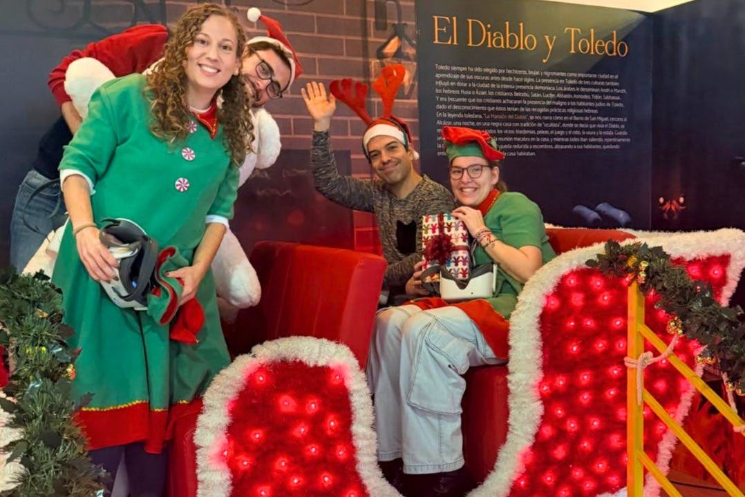 四个人穿着节日服装，背景是节日装饰，对着相机微笑和摆姿势。