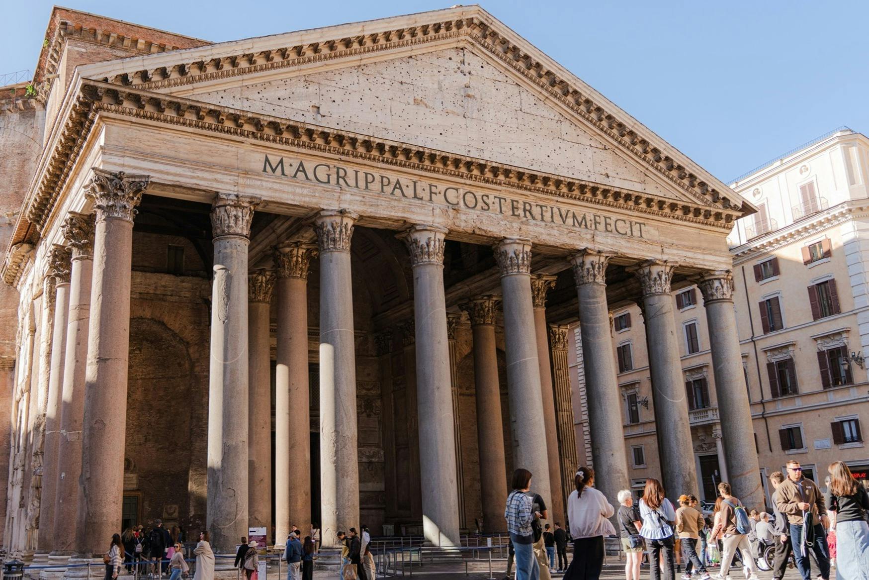 人们站在罗马万神殿前，大柱子和台阶上的铭文。