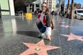 Una turista de la zona del Paseo de la Fama de Hollywood está feliz con su propia réplica de la estrella personalizada para una foto.#single